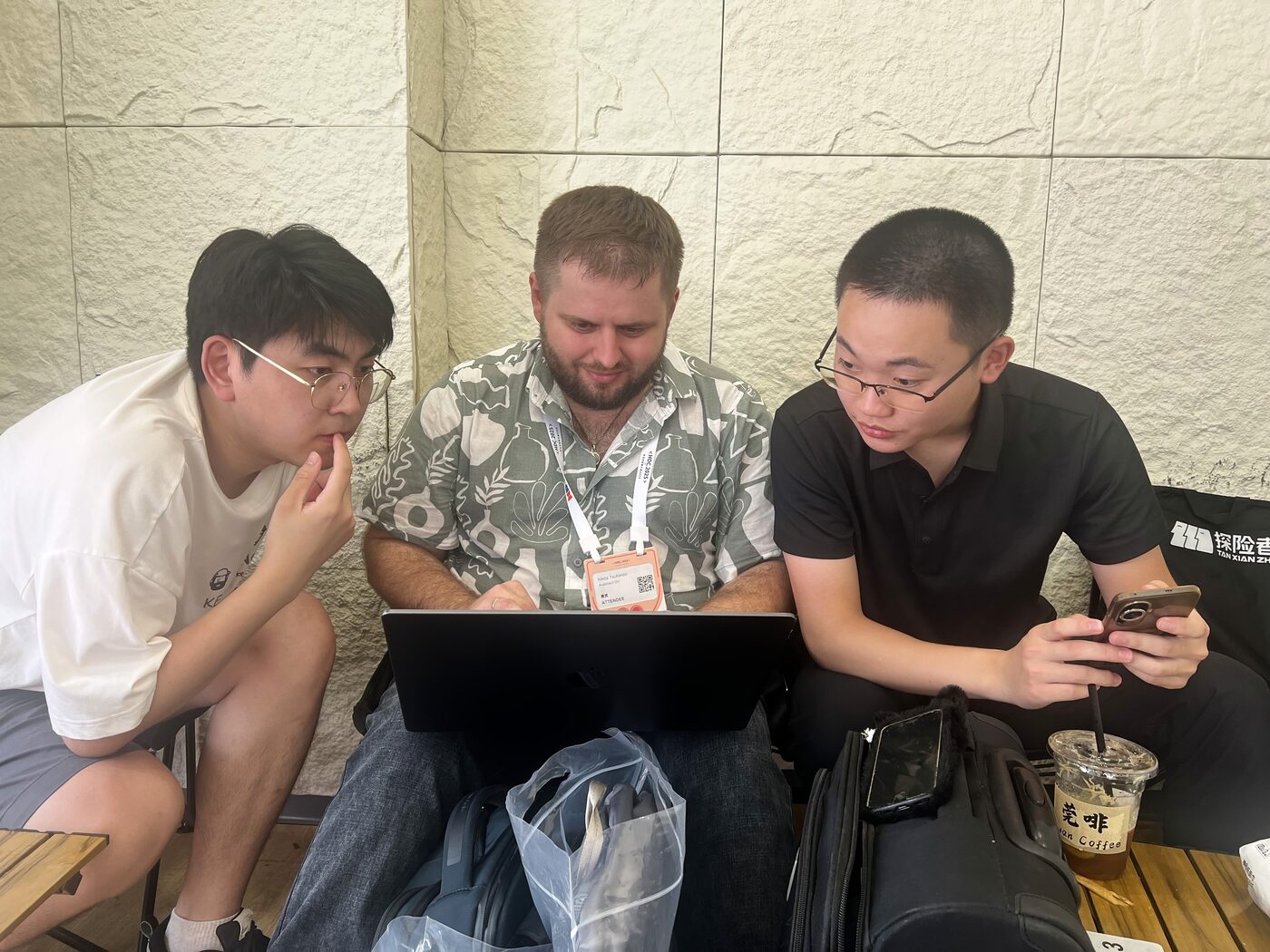 Three developers working through a problem together on a laptop at a conference in China